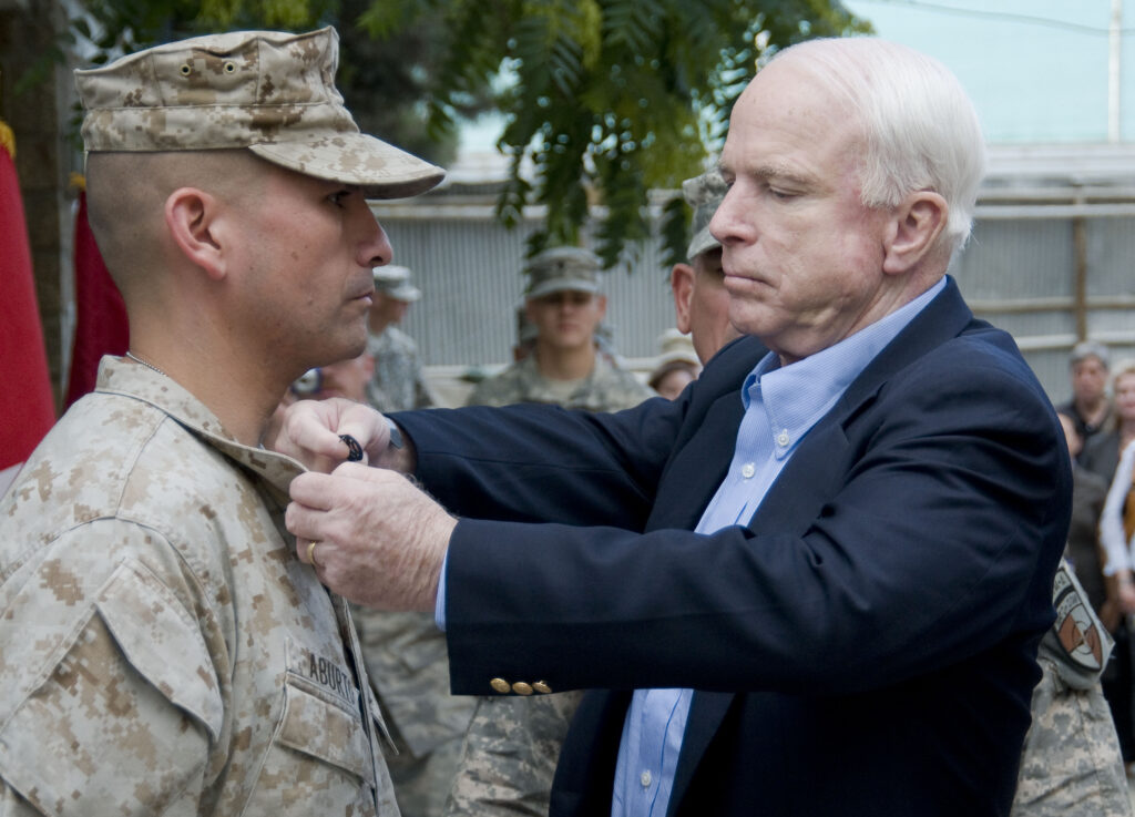 100704-F-1020B-007 Kabul - Senator John McCain, R-Ariz., promotes Marine Staff Sgt. Antonio Aburto during a ceremony at Camp Eggers, Kabul, Afghanistan, July 4, 2010. Senator McCain, along with Senators Lindsey Graham, R-SC., and Joe Lieberman, D-Conn., helped present several combat infantry badges to troops stationed at Camp Eggers.  (U.S. Air Force photo by Staff Sgt. Sarah Brown/RELEASED)
