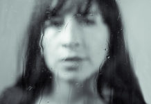 6 Ways Trauma Might Inform Your Current Life woman out of focus with rain on glass