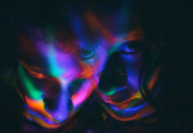 Ending The Silence Around Psychedelic Therapy Abuse Photograph of two faces in psychedelic colors with dark background