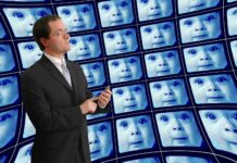 A Dystopian Vision of Psychiatry’s Future photo of man in suit standing in front of a wall of TVs with distorted babies' faces on them