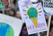 What Is Climate Distress—And What Can Therapists Do About It? A sign at a climate change protest reads "NOT COOL" and depicts Earth as melting ice cream