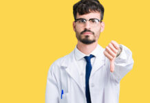 Collateral Damage: The Negative Impact of Antidepressants on New Zealand Youth Young professional scientist man wearing white coat over isolated background looking unhappy and angry showing rejection and negative with thumbs down gesture. Bad expression.