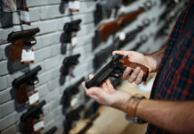 Gun Owners At Risk for Suicide Less Likely to Be Detected by Screening Man holds handgun in gun shop.