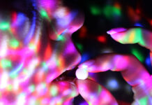 The Powerful Allure of Psychedelics in Today’s Disenchanted World Close up of fingers putting a pill into a mouth. Colored lights all around