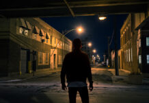 Inside A Forensic Psychiatry Unit: Where I’ve Come From and Where I’m Going A man, silhouetted, seen from the back, standing in a dark city street overpass