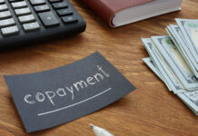 Eliminating Copayments Doubles Psychologist Visits, Decreases Suicide in Young Adults Close-up of the wood top of a desk. On it: money (bills), a calculator, a notebook, and prominently featured, a black business card reading in white text, underlined, "copayment."