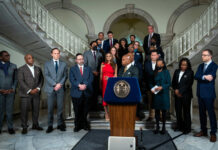 Consumer Advisory Board Chair: NYC Mayor Adams Did Not Consult With Us on New Mental Health Policy A photo of Mayor Eric Adams at a podium, with many other people behind him wearing suits.