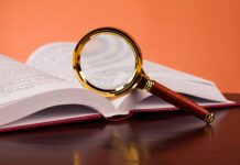 Critical Psychiatry Textbook, Chapter 1: Why a Critical Textbook of Psychiatry? Photo of a magnifying glass sitting on an open textbook
