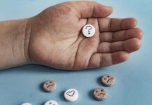 Seriously Misleading Network Meta-analysis in Lancet of Acceptability of Depression Pills Close-up of a hand holding a tablet with a question mark on it. Below, scattered tablets with frowns or hearts.