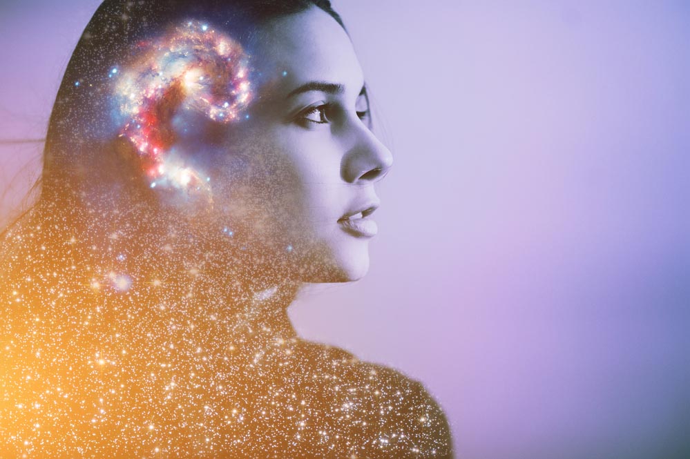 Multiple-exposure portrait of a young woman's face with galaxy inside head