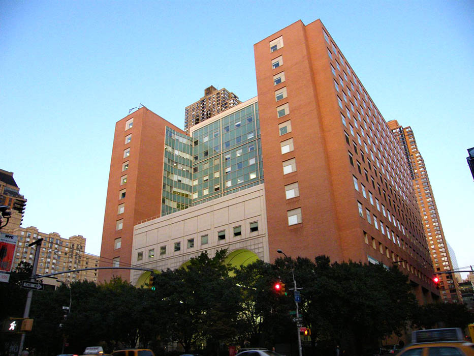 A monolithic building rises above a New York City street in the daytime