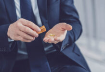 Critical Psychiatry Textbook, Chapter 8: Depression and Mania (Affective Disorders) (Part One) Close up photo depicting a man in a suit pouring two pills into his open palm