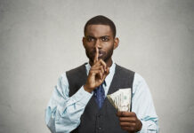 Psychiatrists: The Criminals Behind the Scenes of the Conservatorship Business Photo of a man in a suit holding money and making a shush sign with his finger on his lips