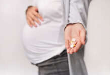 Critical Psychiatry Textbook, Chapter 8: Depression and Mania (Affective Disorders) (Part Fourteen) Photo of a pregnant person's belly clothed in jeans and shirt, hand holding out some pills