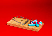 Ten Years Later: Still Shooting the Odds A wooden mousetrap against a red background. Pills are the bait.