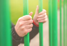 Critical Psychiatry Textbook, Chapter 13: Forced Treatment Person behind bars, female hands gripping steel bars, concept of captivity and imprisonment, retro toned, selective focus