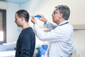 Stock photo of a white-coat male doctor holding a screwdriver to the head of a male patient as if to "fix" him.