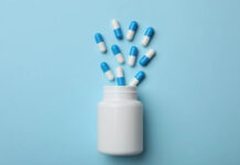 Antidepressant Withdrawal: A Clinician’s Middle View Blue background, white pill bottle, blue and white pills out of the top