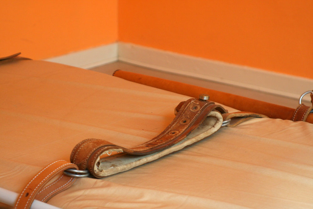 Bed with restraints. Orange colored photograph