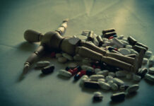 The Lie That Antidepressants Protect Against Suicide Is Deadly An artist's posable mannequin lies flat amongst a pile of pills, dark lighting
