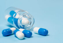 Why Do Only Some People Experience Severe Antidepressant Withdrawal? Blue background, transparent pill bottle spills blue and white pills toward camera