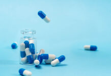 The Challenge of Presenting Antidepressant Risks and Benefits Blue background, transparent pill bottle, blue and white pills out of the top