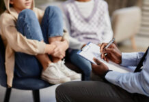 Focusing on Trauma and Involving Families in Care Could Help Prevent Early Death Close up of African-American psychologist taking notes on clipboard in therapy session for children