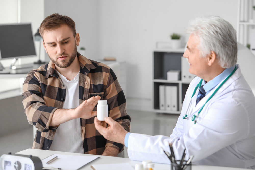 Young man refusing to take prescribed pills in clinic