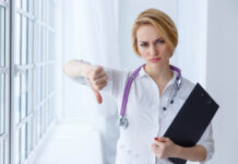 Much of U.S. Healthcare Is Broken: How to Fix It (Chapter 1, Part 2) Closeup portrait, doctor woman, giving thumbs down gesture looking with negative expression, disapproval. Unhappy female health care professional. Emotion facial expression.