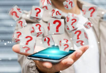 AI Therapy App Fails to Beat Other Interventions in New Study A hand holding a cell phone. Cubes marked with red question marks emerge from the phone