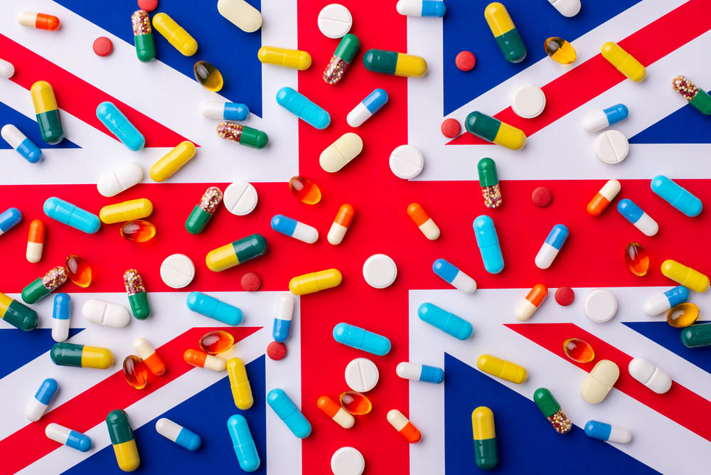 Plenty of capsules and pills laying on a flag of Great Britain. Concept of medicine and heath care in the UK.