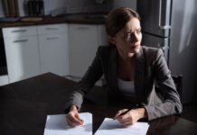 The Social-Emotional Distress Field, or How I Divorced “Mental Health” A woman looks to the side in distress, while holding a wedding band and a pen to sign divorce documents