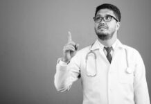 In Defense of Open Dialogue Research Studio shot of bearded Persian man doctor against gray background in black and white