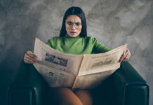 How Danish Journalism Misleads About Psychiatry Photo of outraged shocked woman in stupor reading fake terrible headlines, news about her corporation sitting in armchair isolated grey color wall concrete background