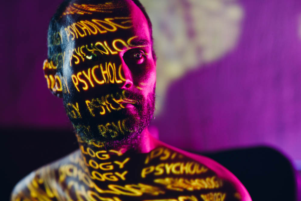 Young adult man with word Psychology on his face in the dark