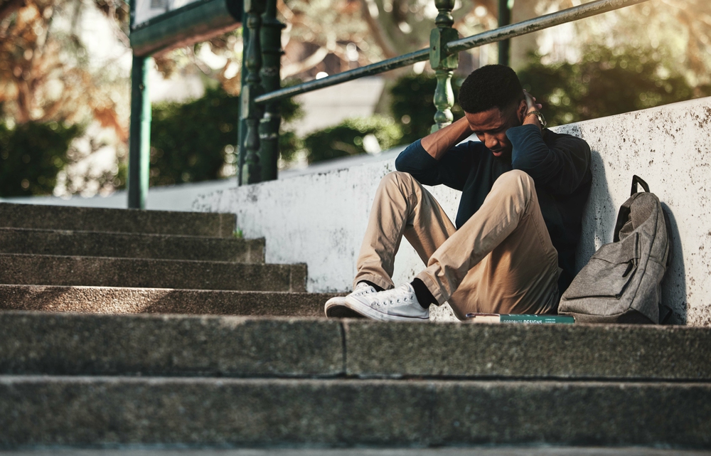 Mental health, depression and anxiety with student on stairs with backpack for failure, fear and mistake. Sad, stress or bullying with black man on steps of college campus for frustrated or problem.