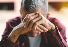 Elder Eyes Wide Shut An older man holds his hands together obscuring his face, head dropped in sadness