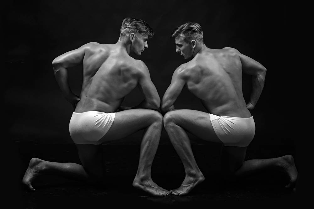 Two similar looking men flexing muscles in black and white