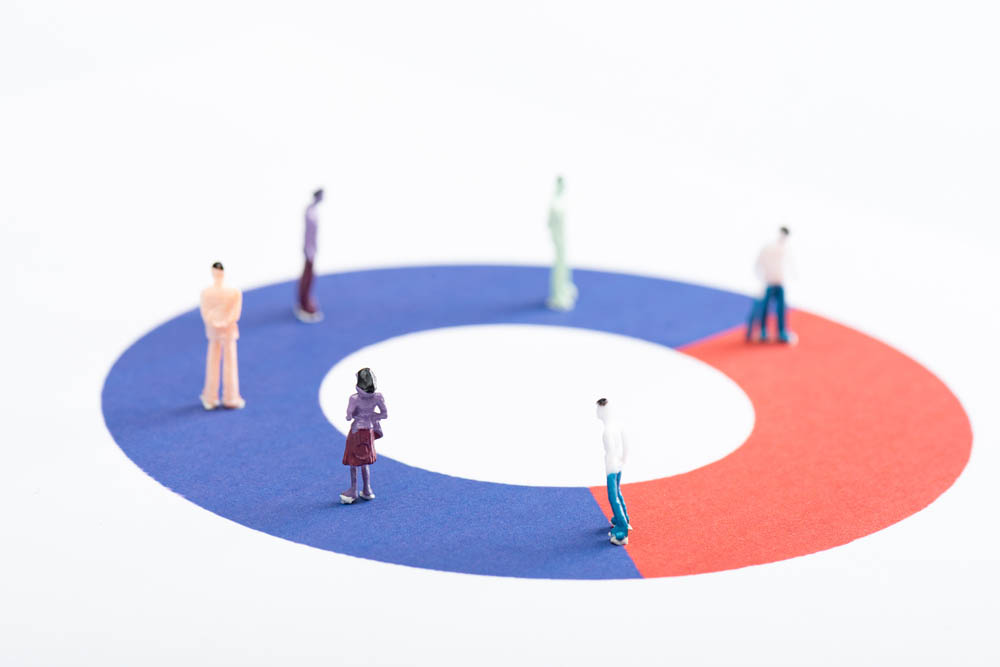 Miniature people walk in circles atop a pie graph