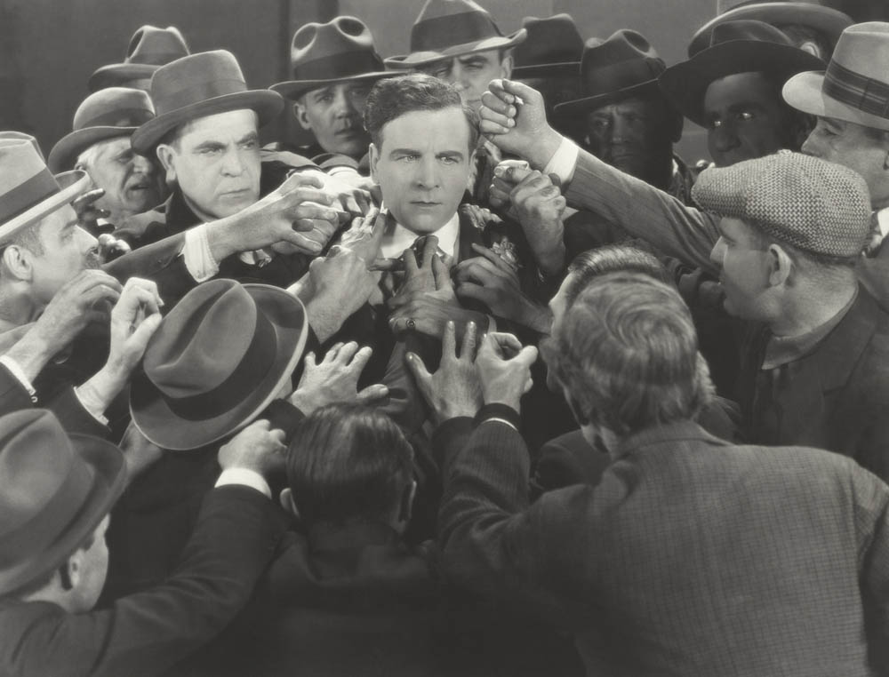 Black and white photo of a confused mob of people with one serene face in the middle