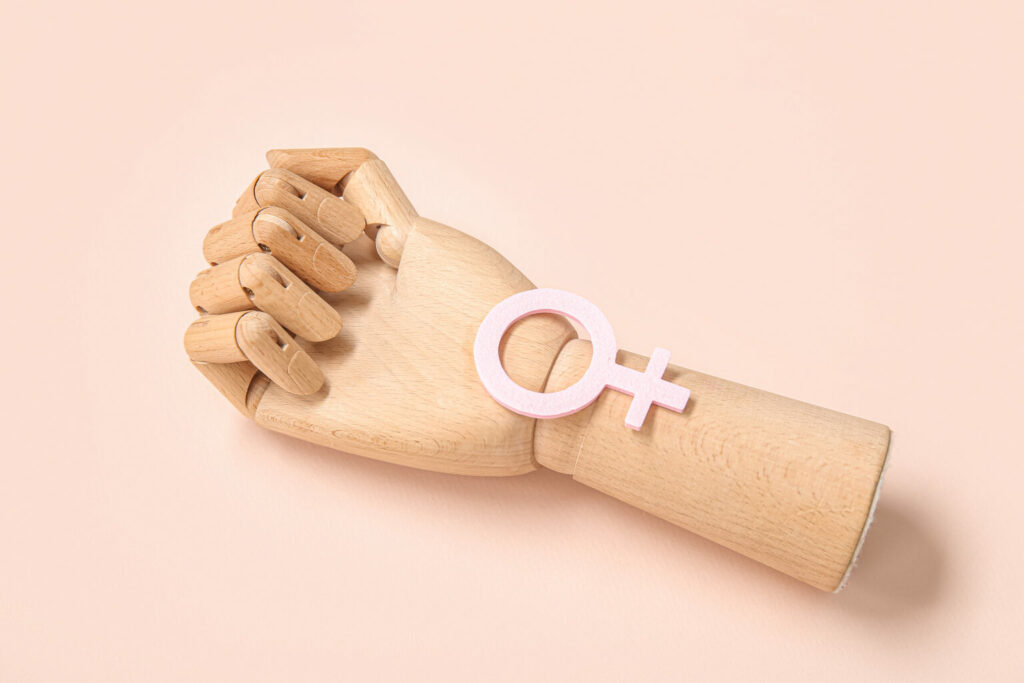 Wooden hand with female gender symbol on pink background