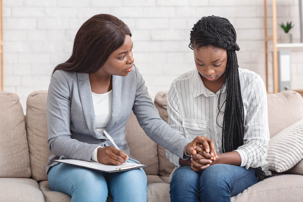 Professional Support. Psychologist comforting depressed female patient during therapy session in office