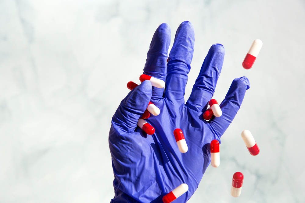 Pills falling out of a doctor's gloved hand