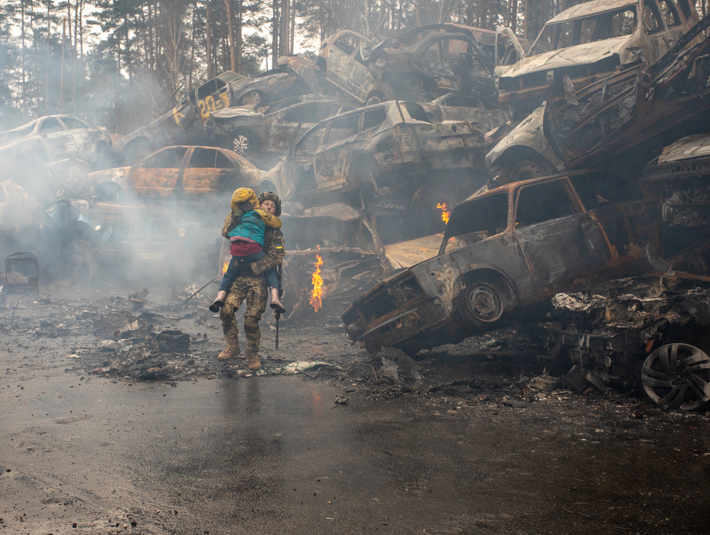 IRPIN, Kyiv region Ukraine - 22.04.2022: Car graveyard. Military woman helping the child to evacuate. russia's war against Ukraine — Stock Editorial Photography
