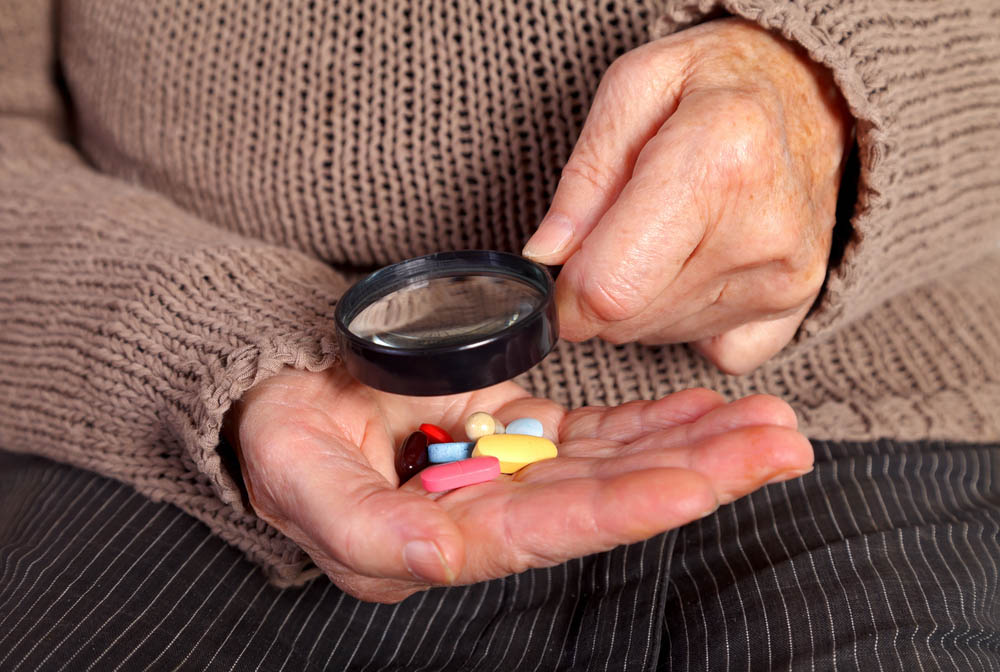 Closeup of pills in hand, a magnifying glass