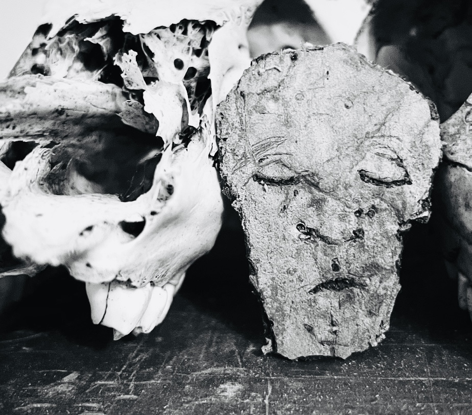A black and white photo of what looks like an unhappy face on a piece of rock or concrete