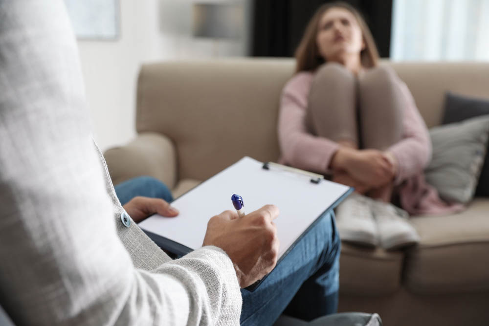 Professional psychotherapist and patient in office, focus on hands with clipboard