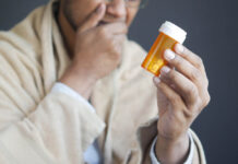 Half of Those Who Take Antidepressants Are Labeled “Treatment Resistant” A person, out of focus, holding a pill bottle in focus