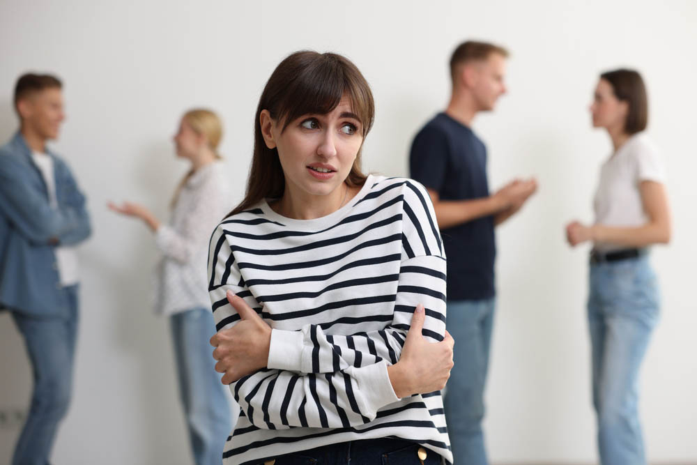 Young woman feeling uncomfortable among people indoors, selective focus