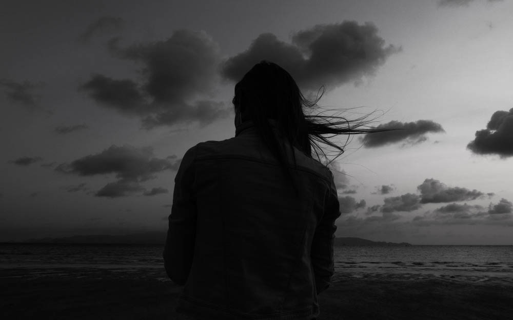 Alone woman at the beach one twilight time looking out to sea